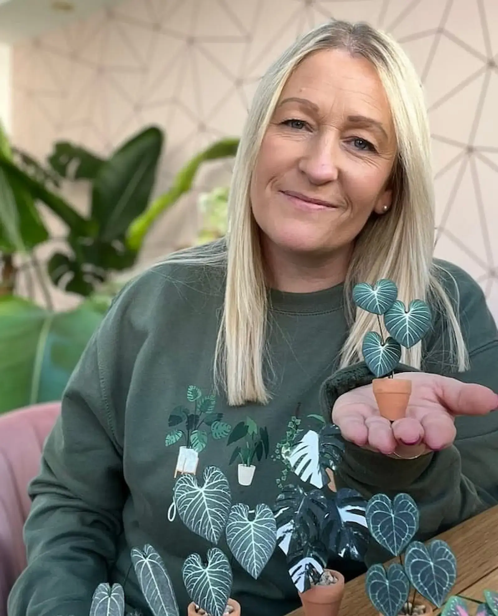 Nicole holding a miniature paper anthurium plant in a tiny terracotta pot.